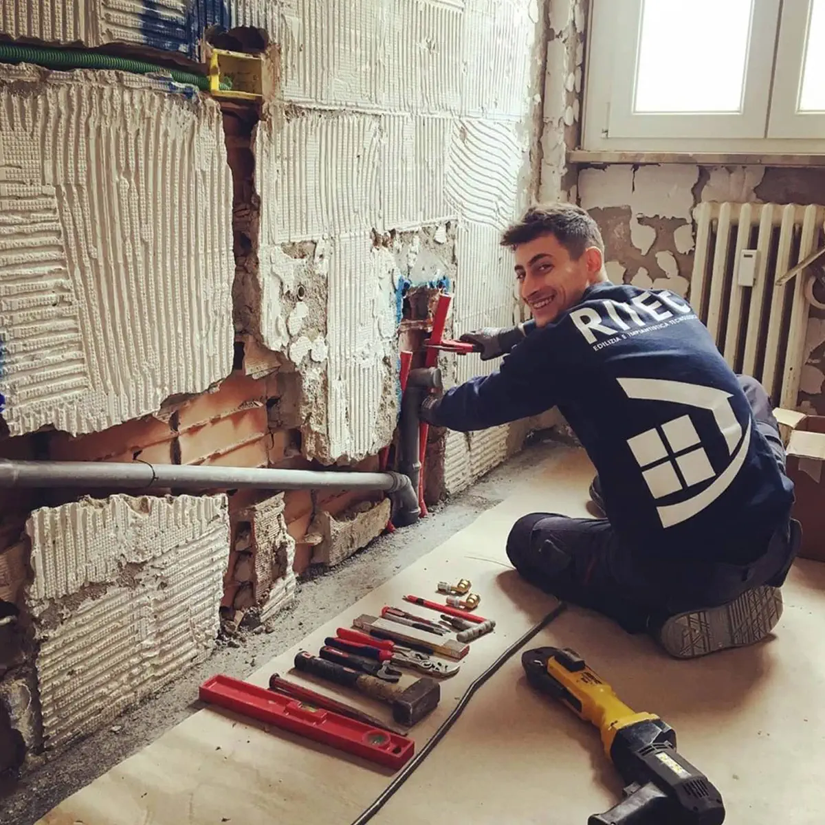 installazione impianto idraulico Un ragazzo giovane e sorridente del team ritec installa l'impianto idraulico in un bagno domestico